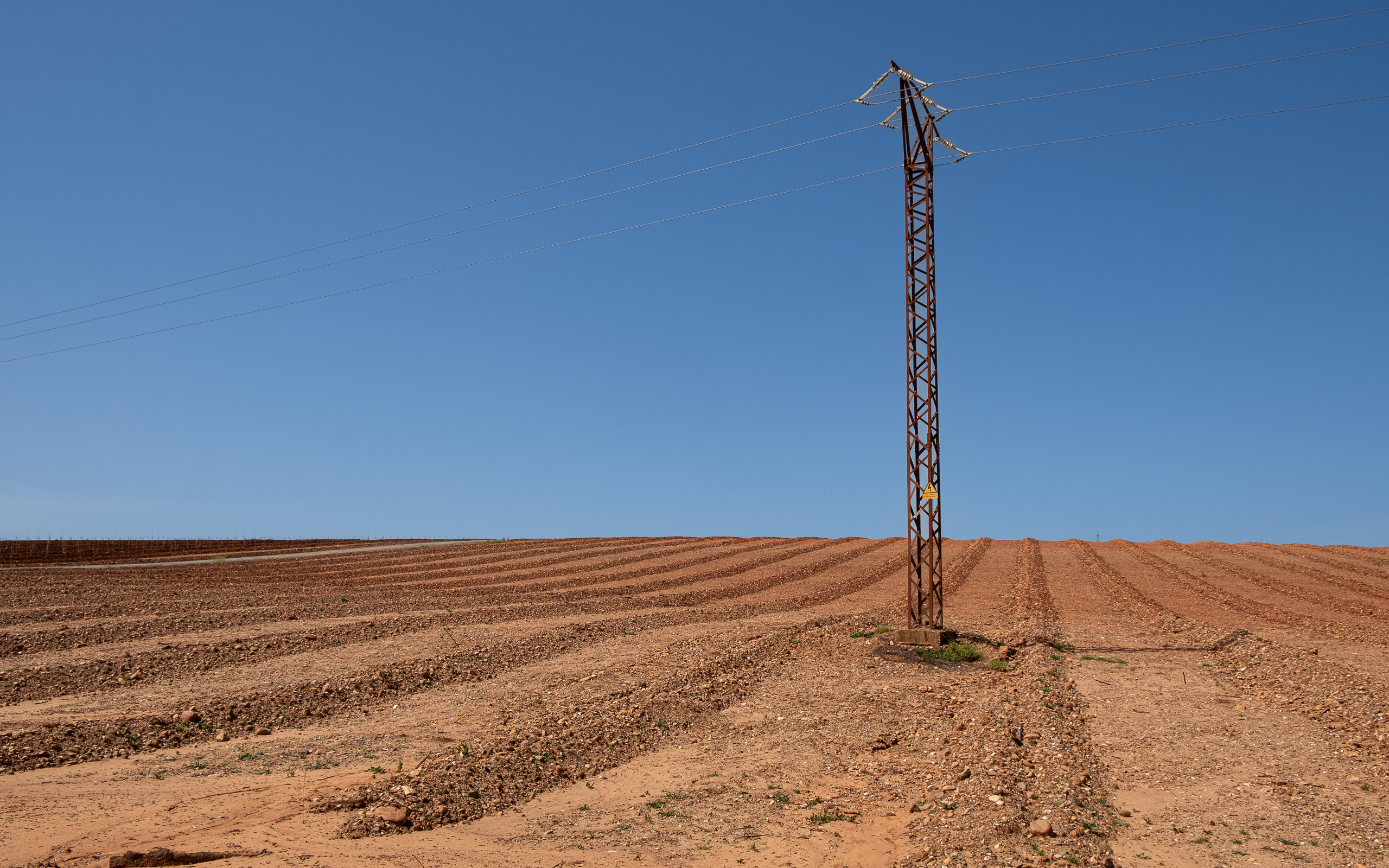 Rotes Ackerland kurz vor Córdoba – einsamer Strommast im Feld